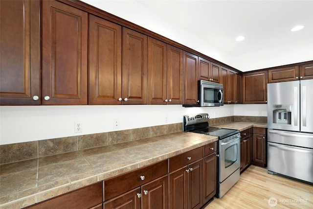 kitchen with dark brown cabinetry, light wood finished floors, recessed lighting, and appliances with stainless steel finishes