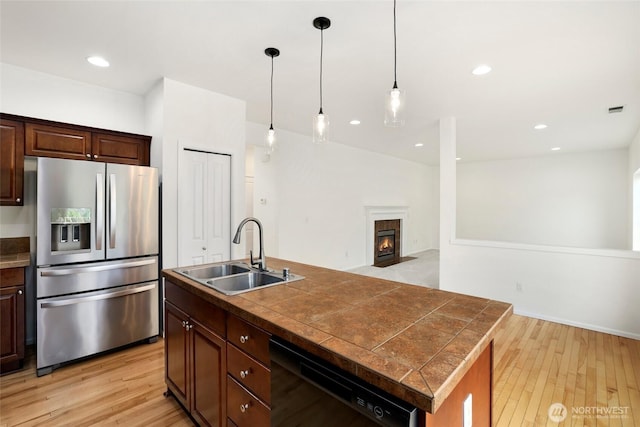 kitchen with dishwasher, stainless steel fridge, light wood finished floors, and a sink