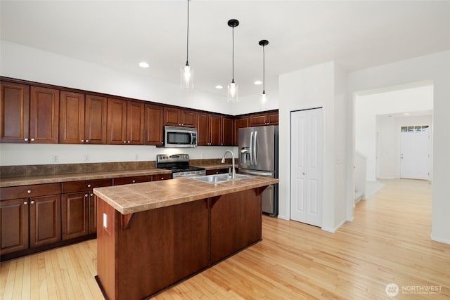 kitchen featuring light wood-type flooring, recessed lighting, appliances with stainless steel finishes, a kitchen breakfast bar, and a sink