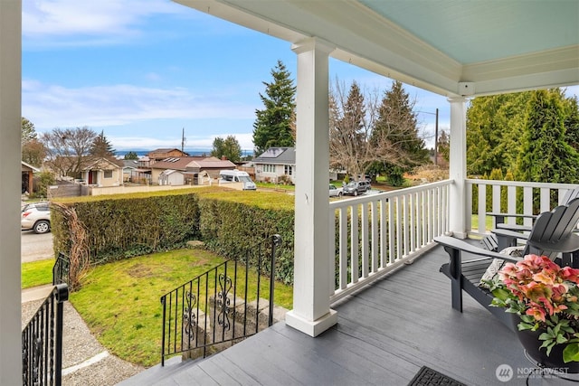 wooden deck with a yard, a residential view, and a porch