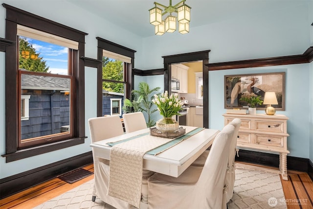 dining area featuring visible vents, baseboards, light wood-type flooring, and an inviting chandelier