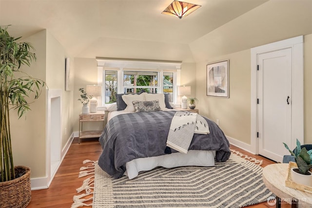 bedroom featuring lofted ceiling, wood finished floors, and baseboards