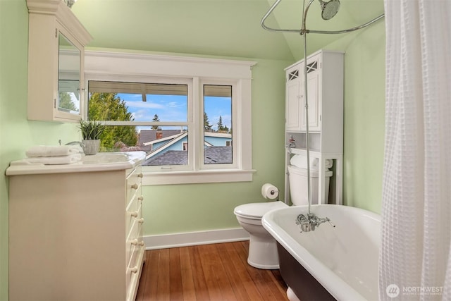 full bath featuring vanity, wood finished floors, baseboards, a soaking tub, and toilet