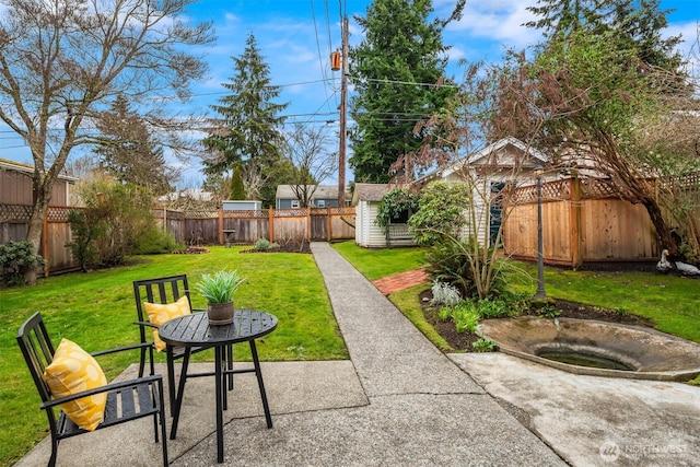 view of yard with an outdoor structure, a fenced backyard, and a patio