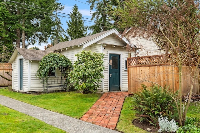 view of front of house featuring a front yard, an outbuilding, and fence