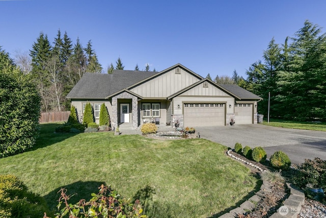 craftsman inspired home with a front lawn, aphalt driveway, fence, board and batten siding, and a garage