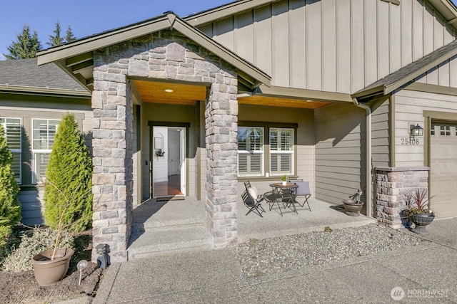 view of exterior entry with an attached garage, board and batten siding, and stone siding