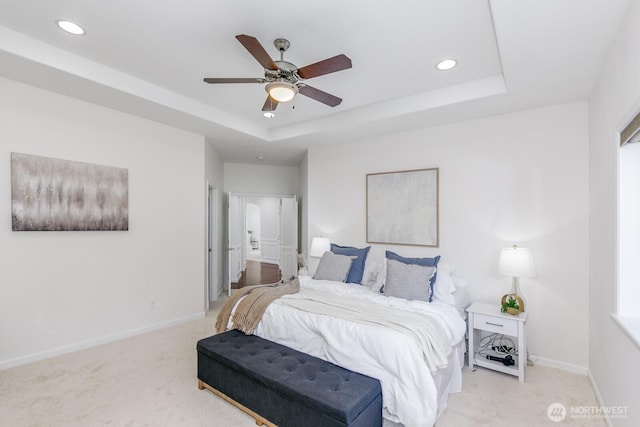 bedroom with recessed lighting, a tray ceiling, baseboards, and light colored carpet