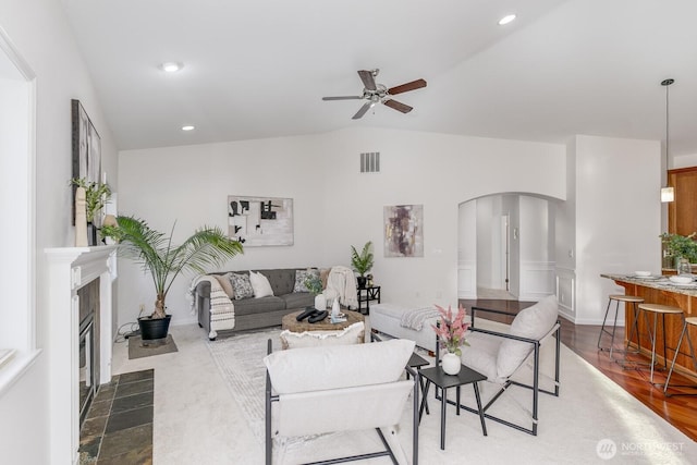 living room with visible vents, lofted ceiling, a premium fireplace, recessed lighting, and arched walkways