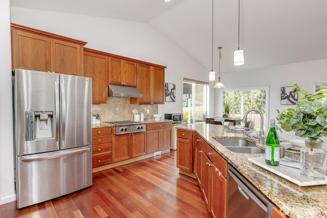 kitchen featuring brown cabinetry, a sink, under cabinet range hood, appliances with stainless steel finishes, and light wood-type flooring