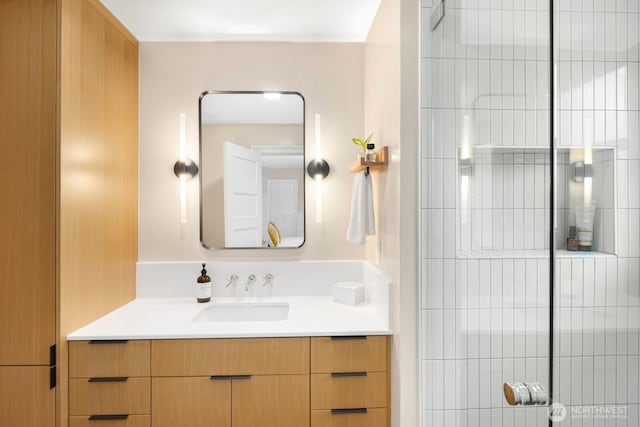 full bath with tiled shower and vanity