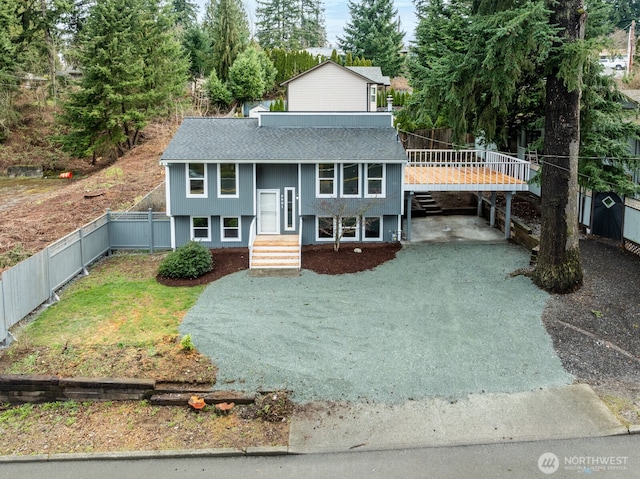 split foyer home featuring fence, driveway, and roof with shingles