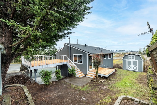 back of house with an outdoor structure, a deck, and a shed