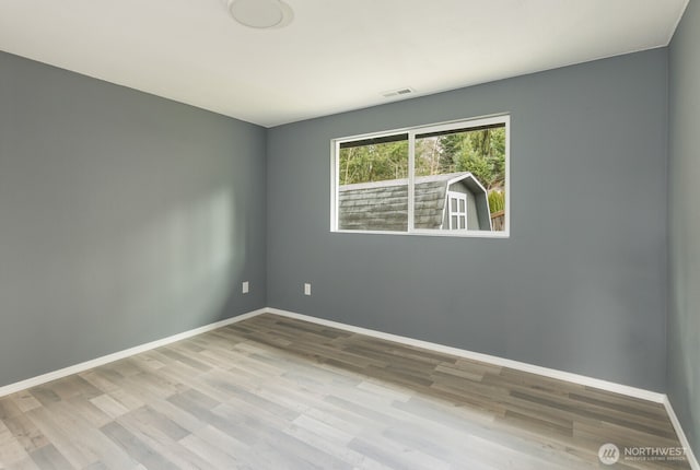 empty room with visible vents, baseboards, and wood finished floors