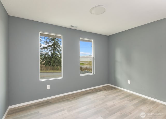 spare room with visible vents, baseboards, and wood finished floors