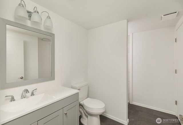 bathroom with vanity, wood finished floors, visible vents, baseboards, and toilet