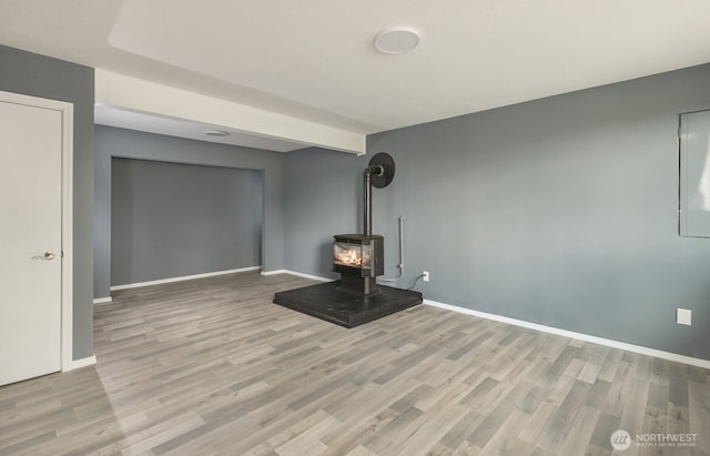 unfurnished living room with a wood stove, baseboards, and wood finished floors