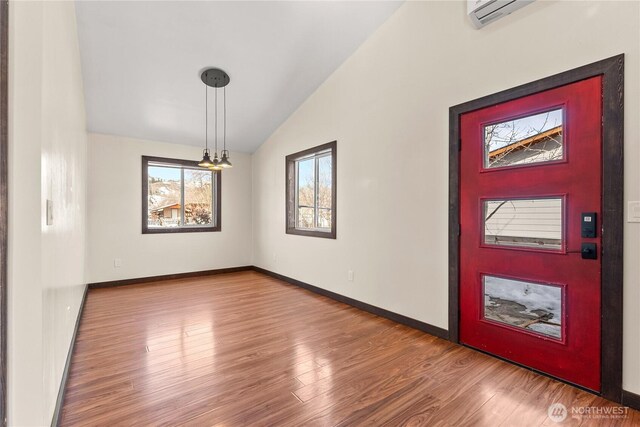 foyer with a wall mounted air conditioner, baseboards, wood finished floors, and vaulted ceiling