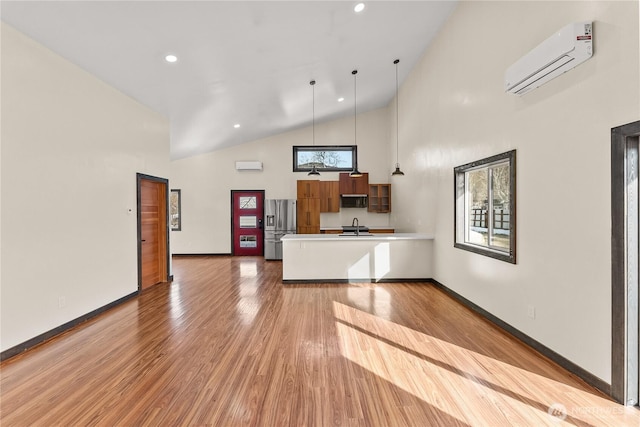 kitchen featuring an AC wall unit, a wealth of natural light, stainless steel fridge with ice dispenser, and a peninsula