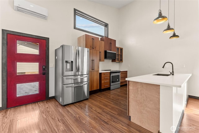 kitchen featuring a wall mounted air conditioner, dark wood-type flooring, a sink, appliances with stainless steel finishes, and brown cabinetry