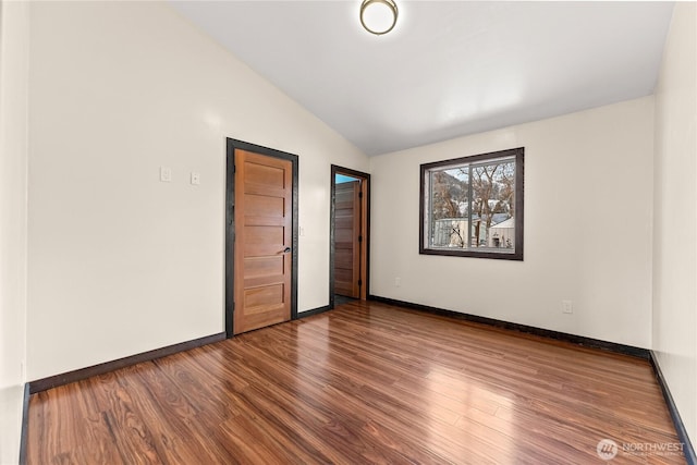 unfurnished bedroom featuring lofted ceiling, wood finished floors, and baseboards