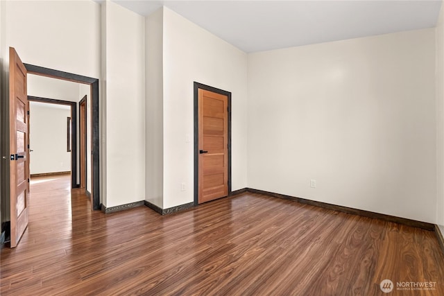 empty room featuring baseboards and dark wood-style flooring