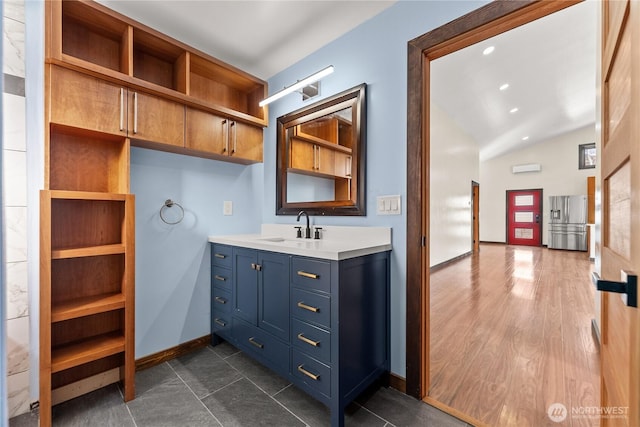 bathroom with vanity, wood finished floors, baseboards, lofted ceiling, and recessed lighting