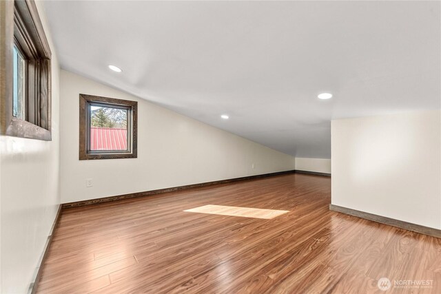 empty room featuring lofted ceiling, recessed lighting, wood finished floors, and baseboards