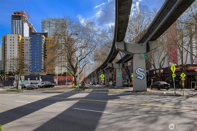 view of road with traffic signs, curbs, a view of city, and sidewalks