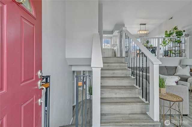 staircase with visible vents and wood finished floors