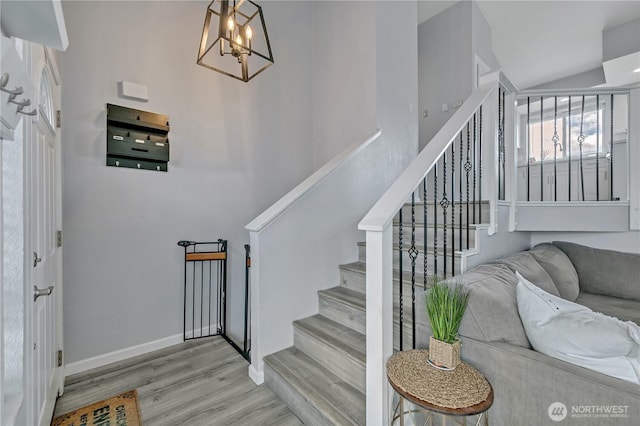 stairway featuring a chandelier, baseboards, and wood finished floors