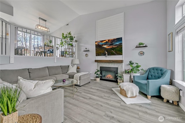 living room featuring a tile fireplace, lofted ceiling, and wood finished floors