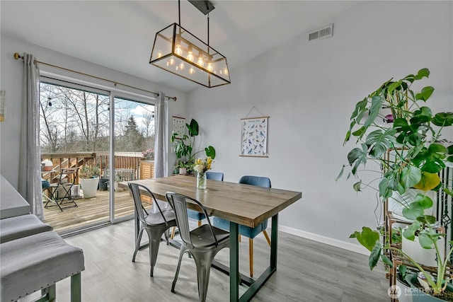 dining room featuring a notable chandelier, visible vents, light wood-type flooring, and baseboards