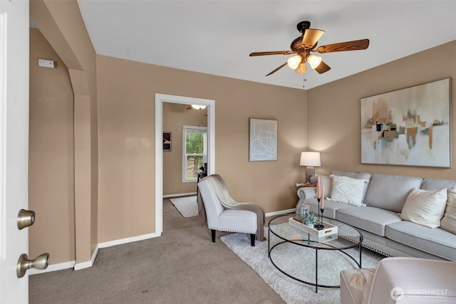 living room featuring baseboards, a ceiling fan, and carpet flooring