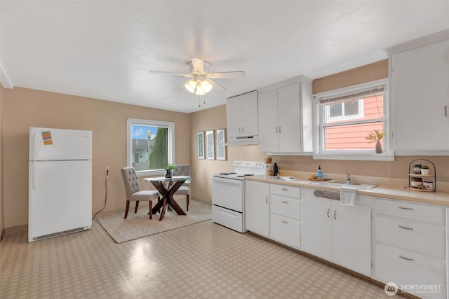 kitchen featuring under cabinet range hood, light floors, light countertops, white appliances, and a sink