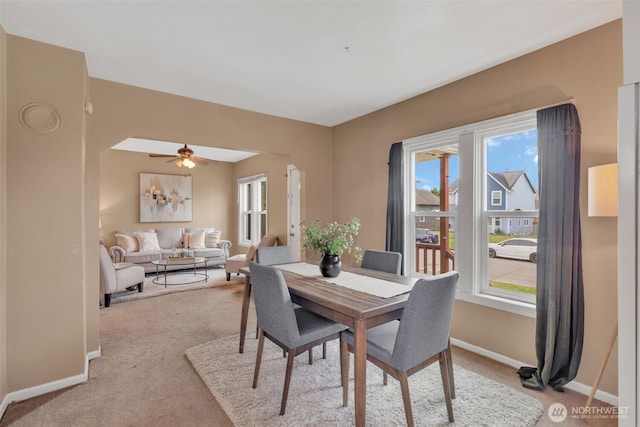 dining room featuring light colored carpet, baseboards, and ceiling fan