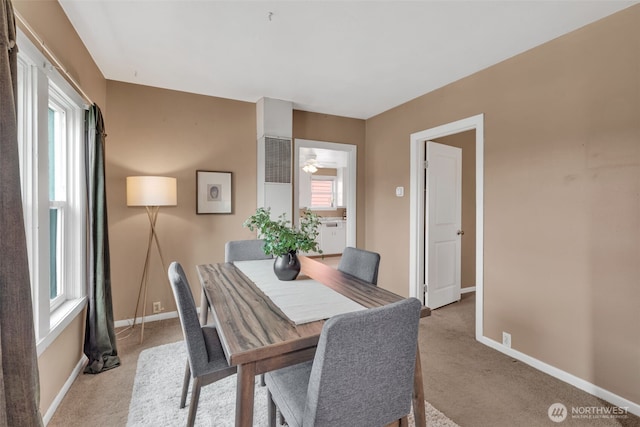 dining space with a wealth of natural light, baseboards, and light colored carpet