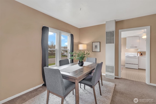 dining space with baseboards and light carpet