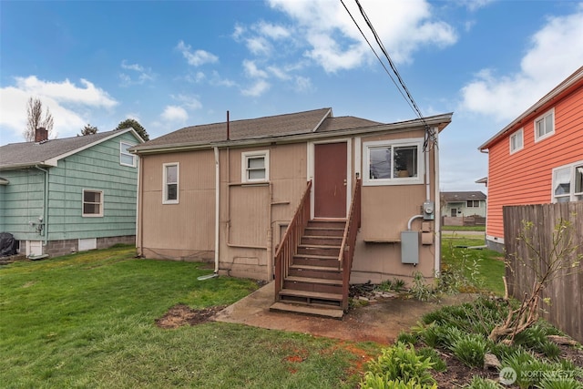 rear view of house featuring entry steps, a yard, and fence