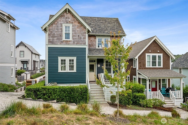 shingle-style home featuring a porch and roof with shingles