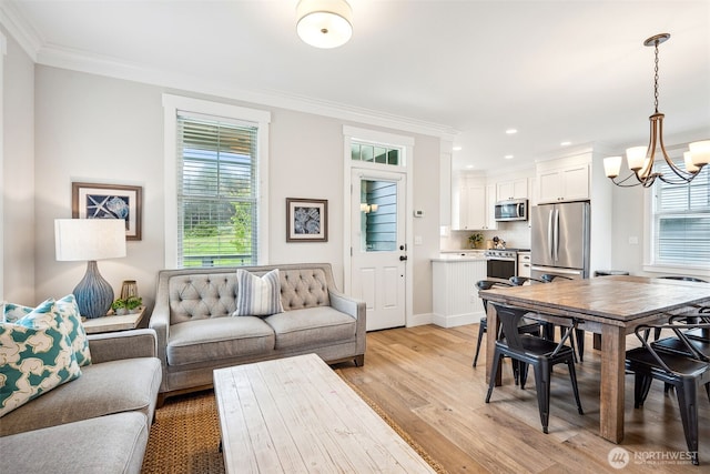 living room featuring baseboards, light wood finished floors, recessed lighting, crown molding, and a chandelier