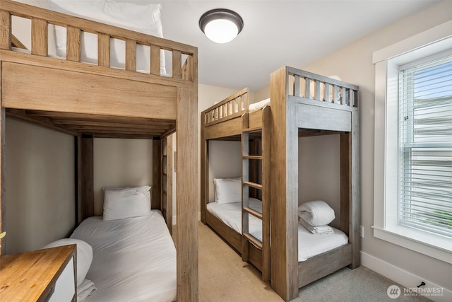 bedroom with baseboards, multiple windows, and light colored carpet