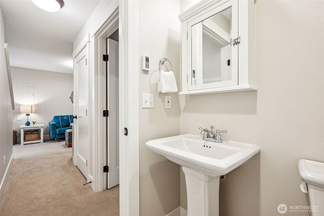 half bath featuring a sink, baseboards, and toilet