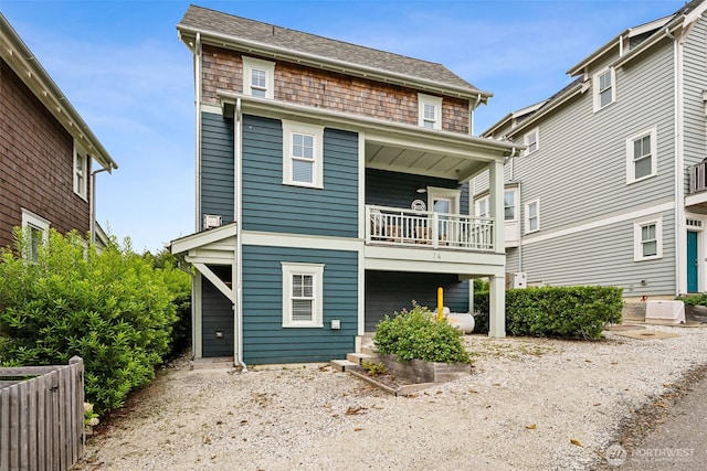 rear view of property with a balcony and a shingled roof