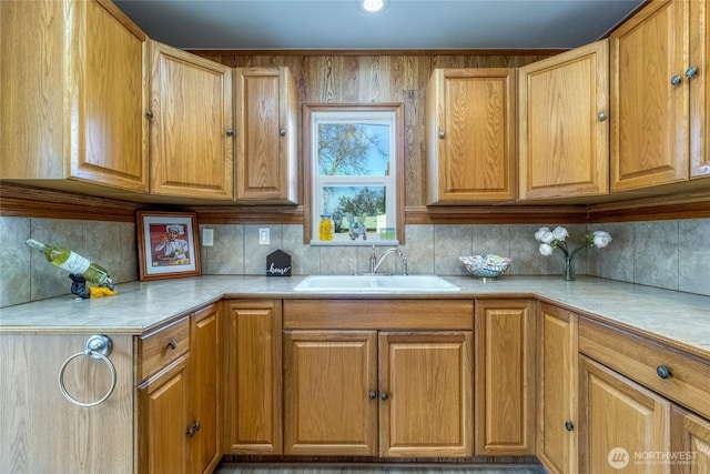 kitchen featuring decorative backsplash, light countertops, brown cabinets, and a sink