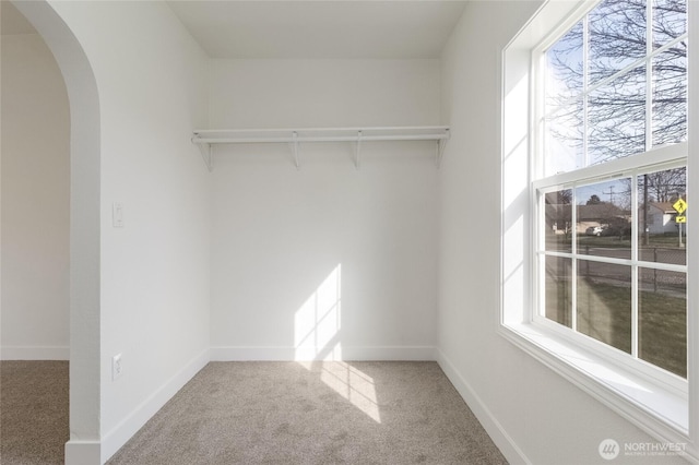 walk in closet with arched walkways and carpet floors