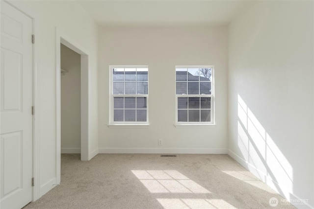 empty room with visible vents, baseboards, and light carpet