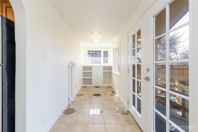 entryway with light tile patterned floors, baseboards, and arched walkways