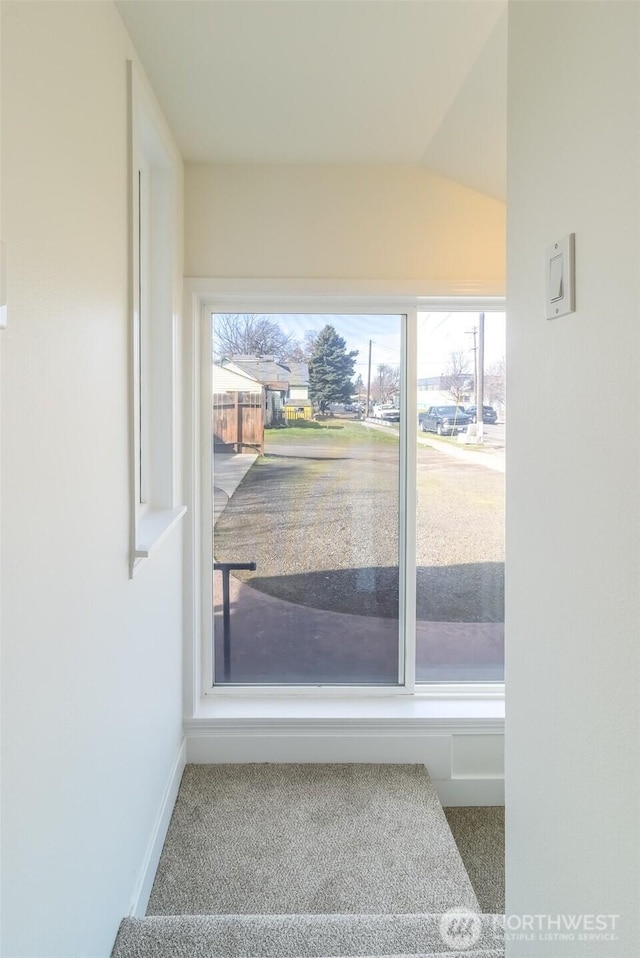 doorway featuring carpet flooring and baseboards