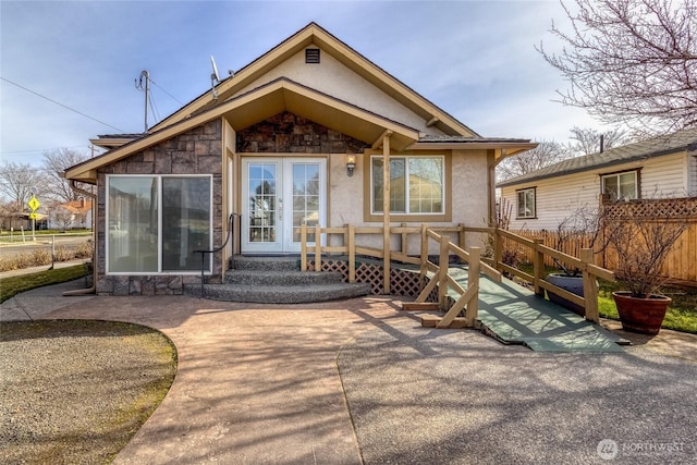 exterior space featuring french doors, stone siding, and stucco siding